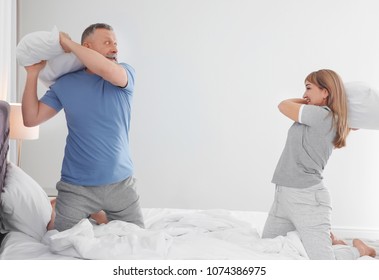 Mature couple playfighting on bed side view photo